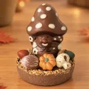 Paddenstoel in chocolade op een potje met truffels, omringd door herfstpralines: eikel, walnoot, pompoen en champignon